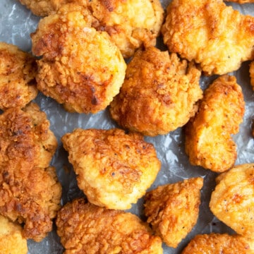 Easy one pan crispy fried chicken bites on tray lined with crumpled paper.