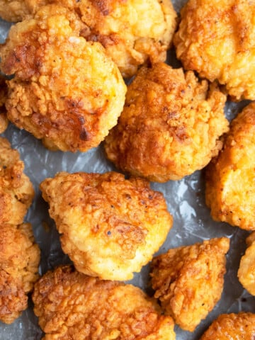 Easy one pan crispy fried chicken bites on tray lined with crumpled paper.