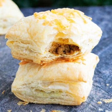 Stack of Ground Beef Puff Pastry (meat puffs or hand pies) on Rustic Gray Background.