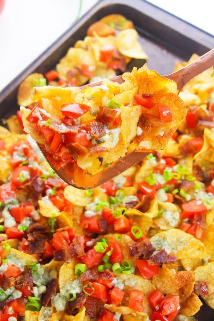 Spoonful of game day appetizer with potato chips and lots of toppings- Closeup shot.