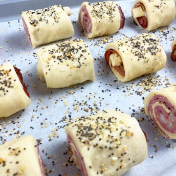 Rolls sprinkled with seasoning on a lined baking tray.