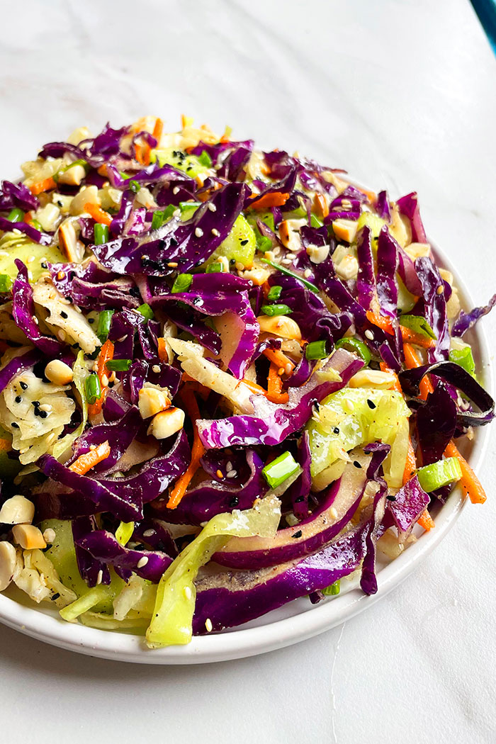 Red Cabbage Salad With Asian Dressing in White Dish on White Background