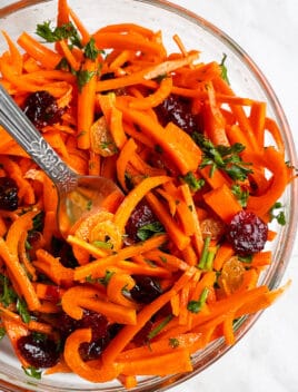 Easy Carrot Raisin Salad With Ginger Dressing in Glass Bowl on White Background