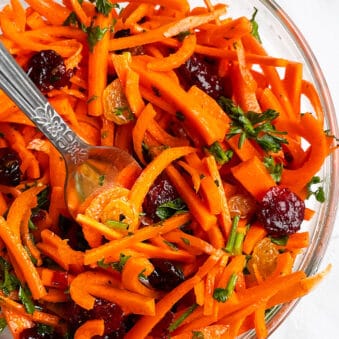 Easy Carrot Raisin Salad With Ginger Dressing in Glass Bowl on White Background