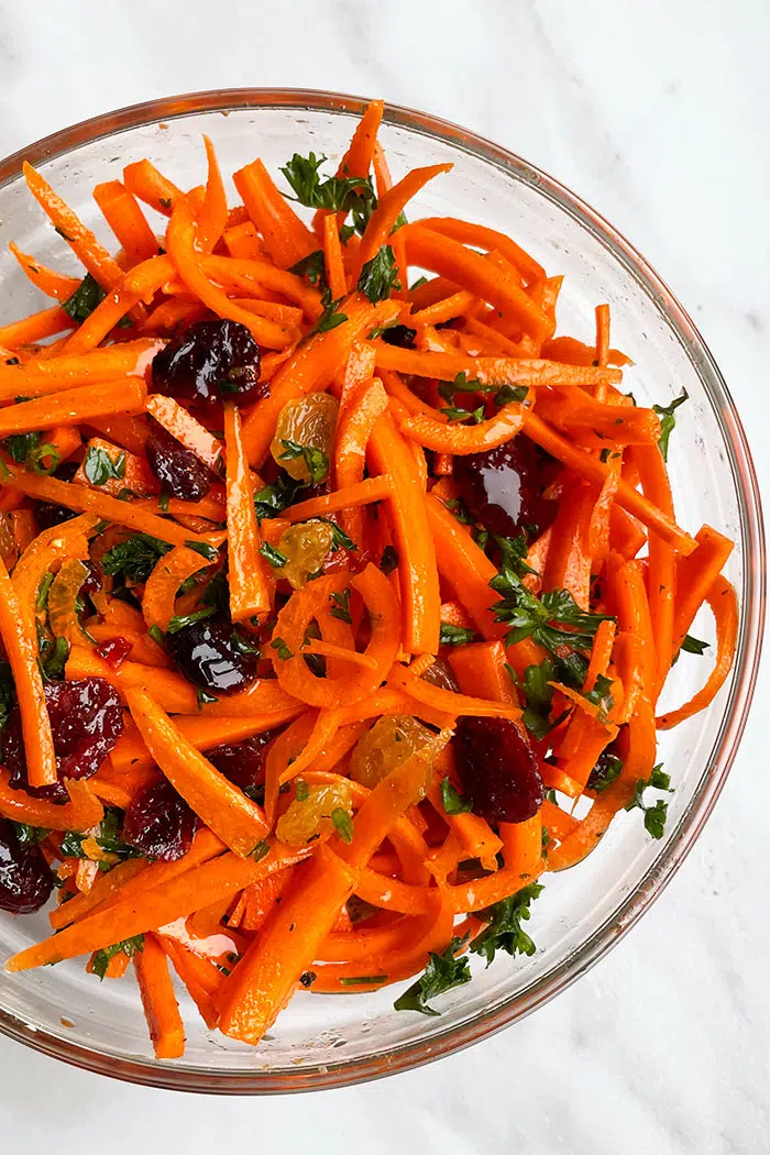 Quick Easy Carrot Raisin Salad With Ginger Dressing in Glass Bowl on White Background