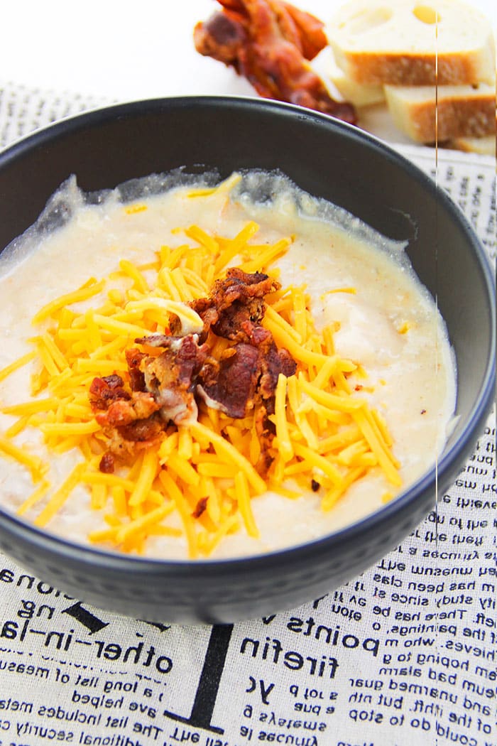 Easy Cheesy Creamy Instant Pot Potato Soup With Bacon and Cheddar Cheese in Black Bowl on Newspaper