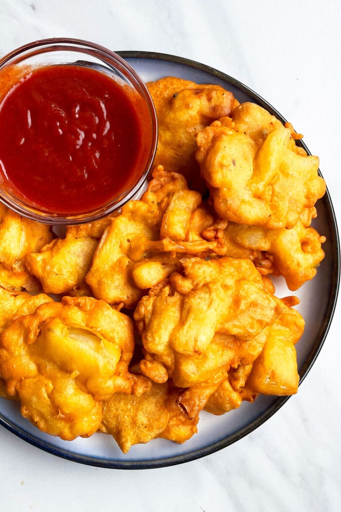 Easy Crispy Onion Fritters in White Dish With Bowl of Dipping Sauce.