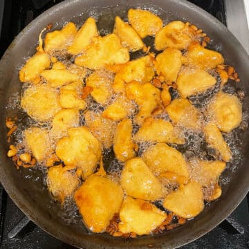 Batter being fried in hot oil in a pan.