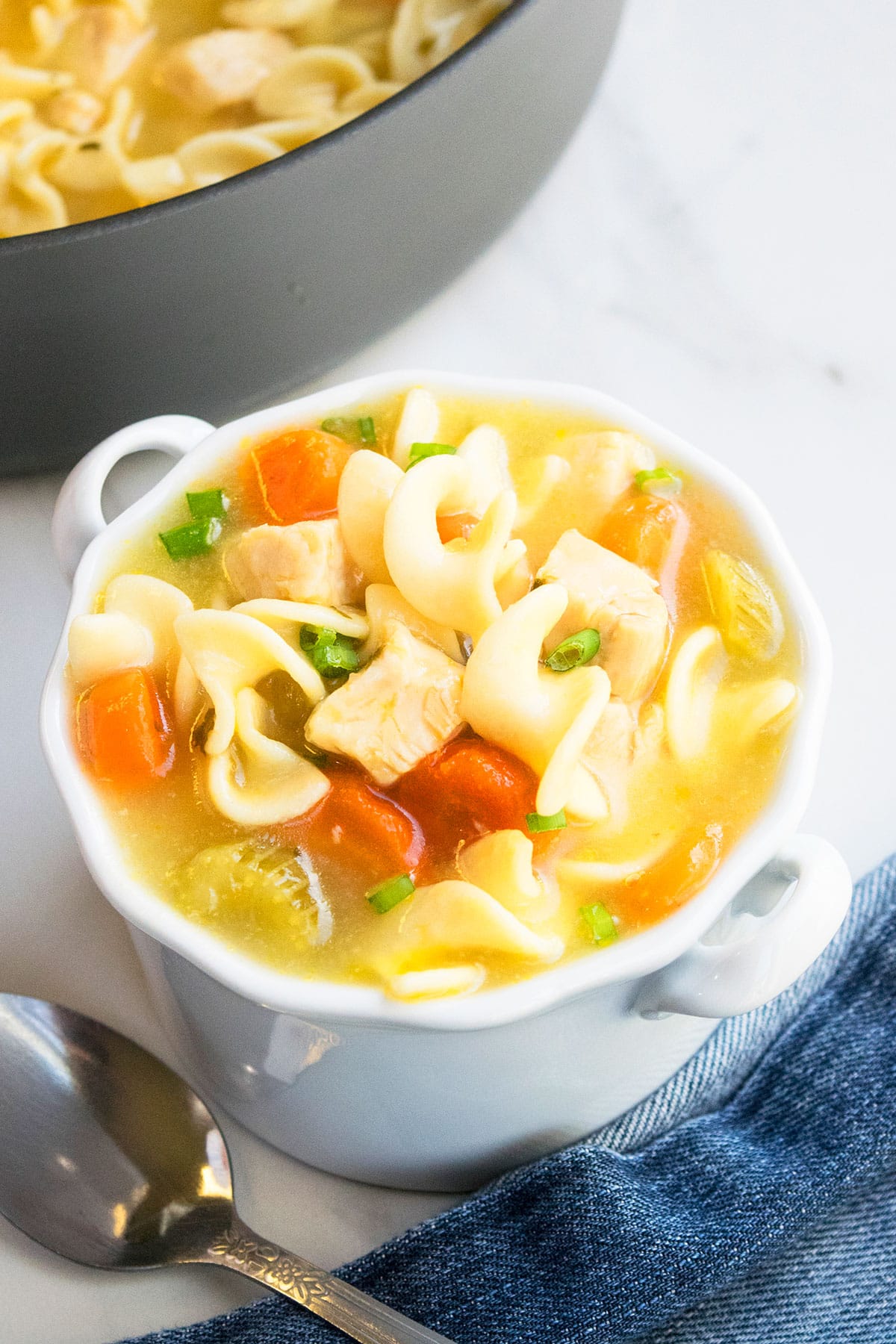 Bowl of Healthy Chicken Soup With Pasta in White Bowl on Marble Background. 