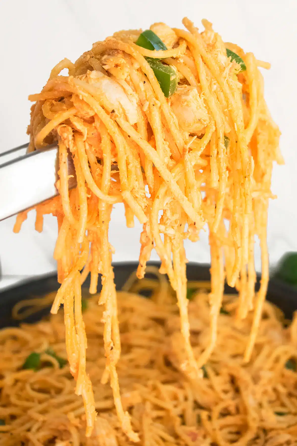 Tongs Holding Pasta over a White Background. 