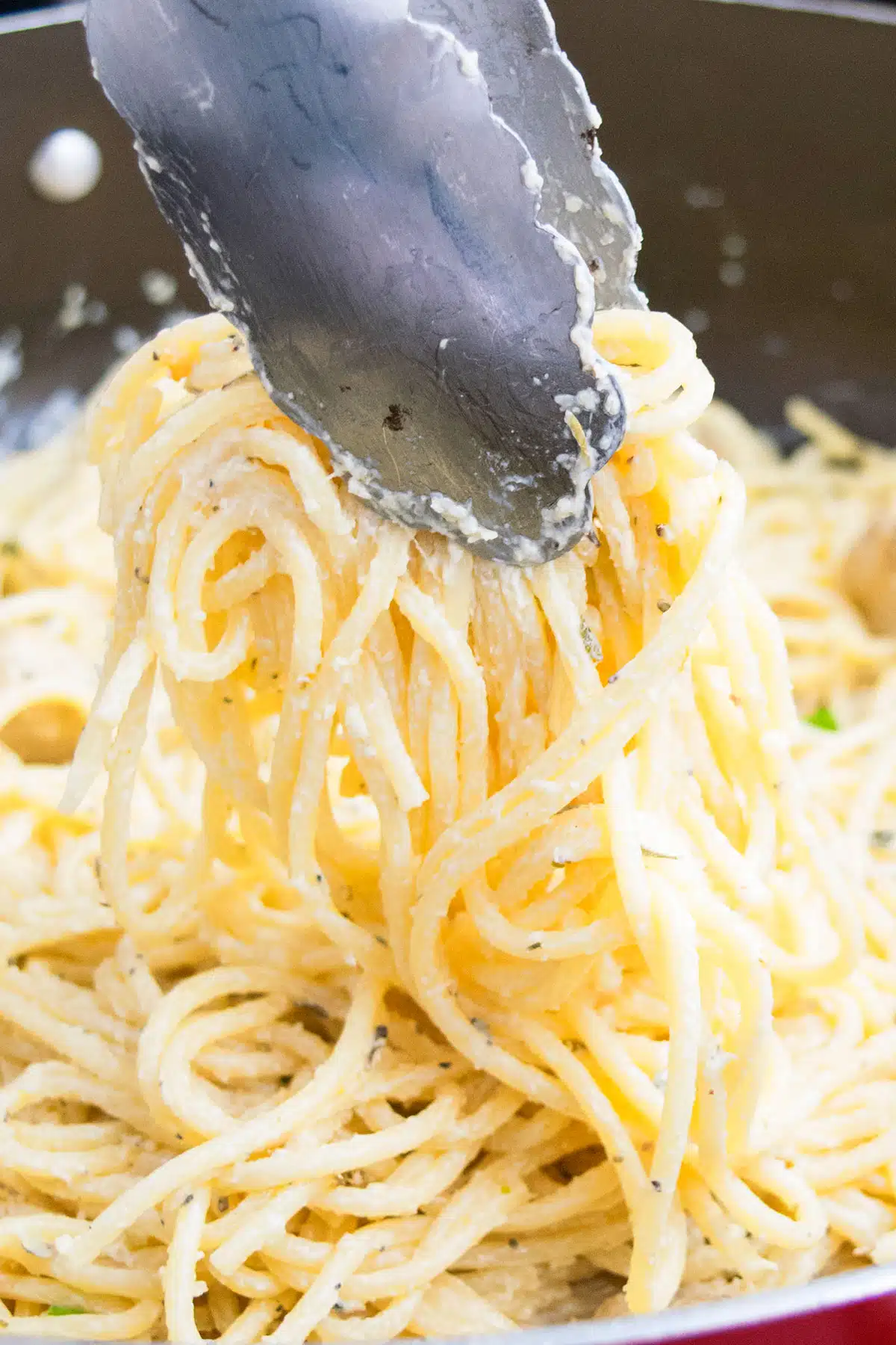 Tongs Full of Creamy Garlic Pasta- Closeup Shot. 