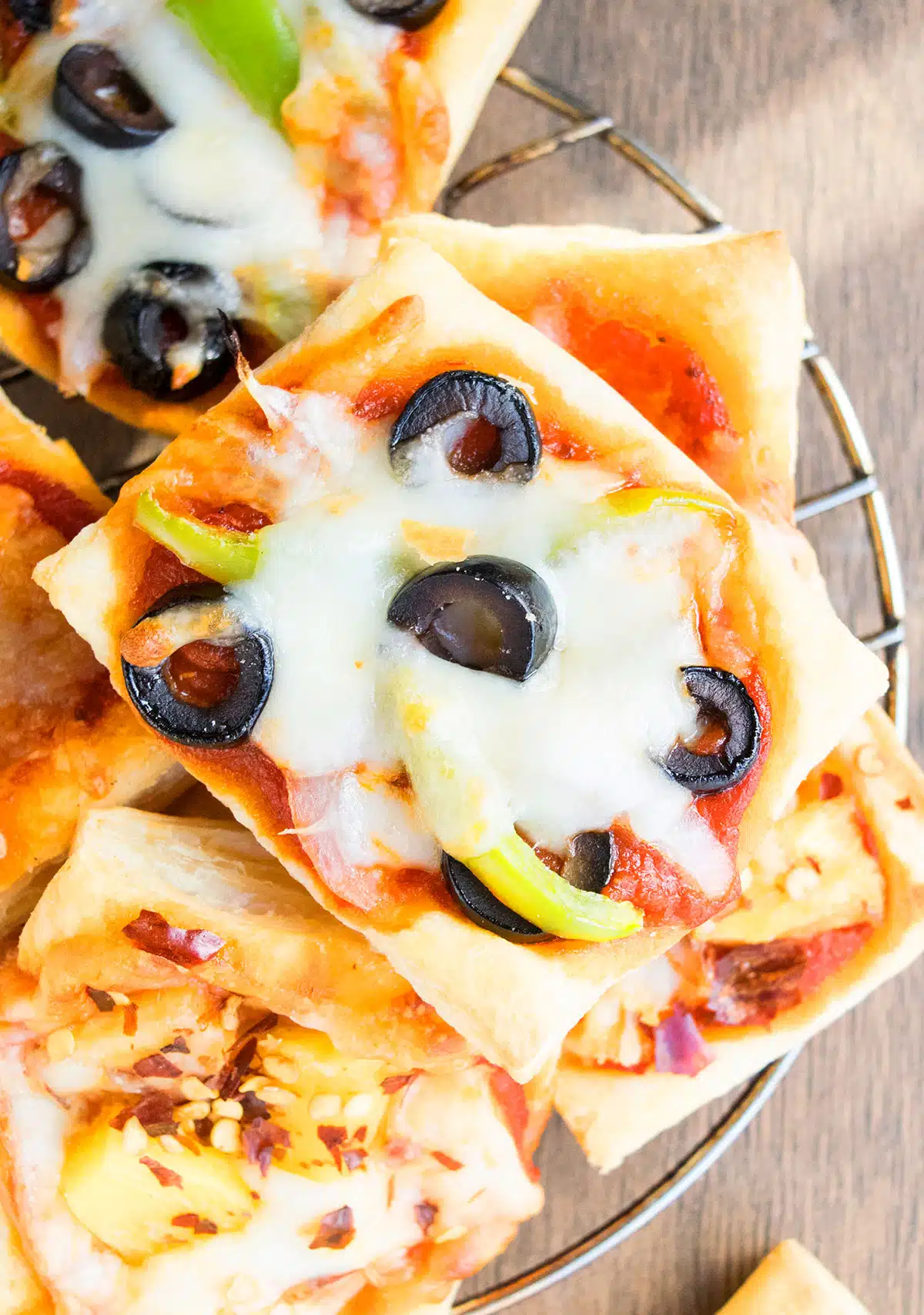 Puff with veggies, olives and melted cheese on cooling rack. 