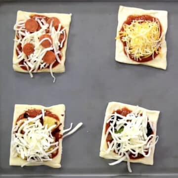 Mini square puffs with toppings on baking tray. 