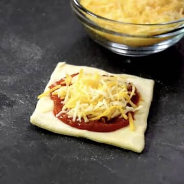 Shredded cheese added on top of the pizza sauce lined dough. 