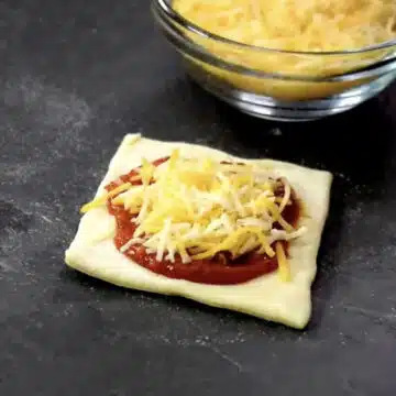 Shredded cheese added on top of the pizza sauce lined dough. 