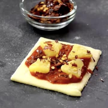 Pineapple and red chili flake toppings added to dough. 