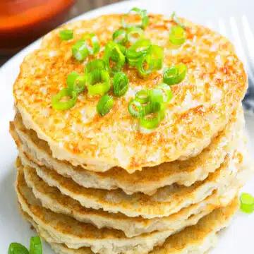 Stack of easy crispy leftover mashed potato pancakes with green onion garnish on white dish.