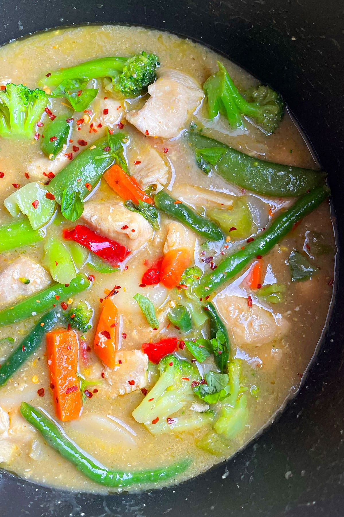 Best Thai green chicken curry with vegetables in black nonstick pot. 