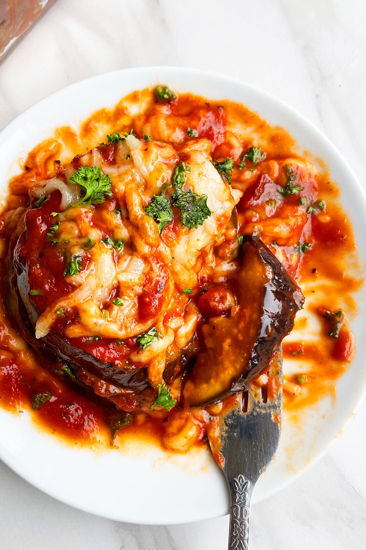 Partially eaten food on white dish with fork. 