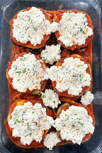 Assembling of layers of eggplants, marinara sauce and cheese mixture in glass baking dish. 