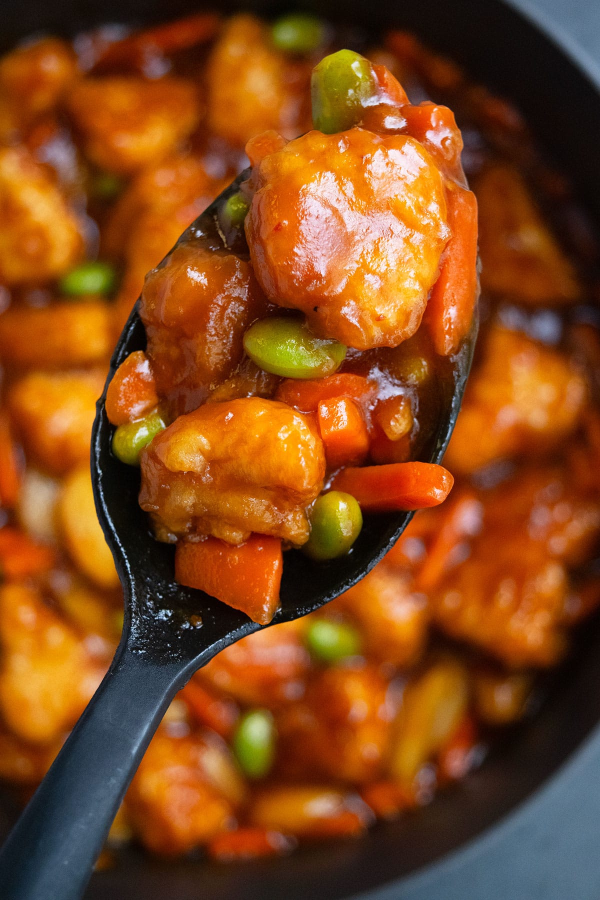 Closeup shot of spoonful of  breaded chicken and vegetables. 