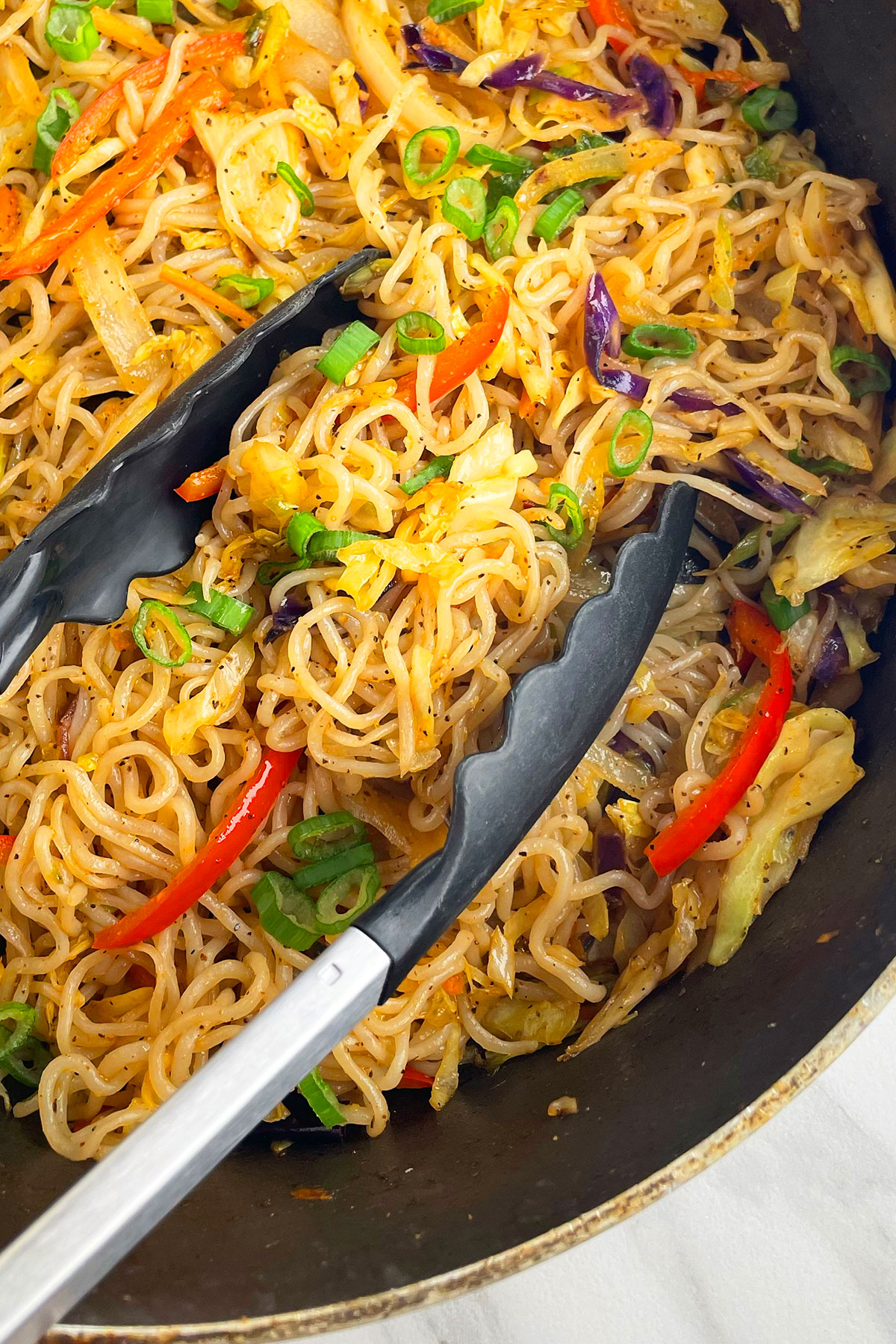Closeup shot of Asian noodles in pot with tongs.