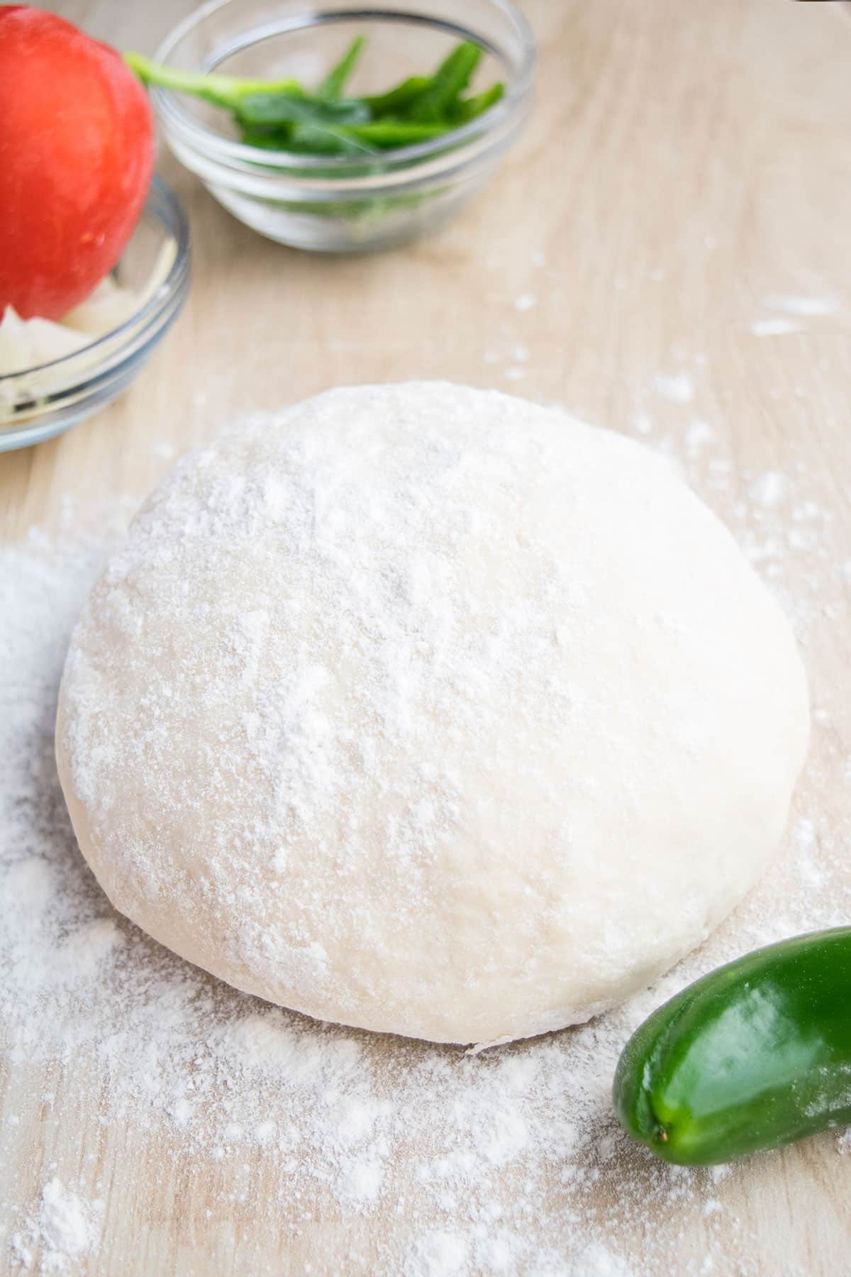 Ball of 2 ingredient yogurt pizza dough on a wooden tabletop. 