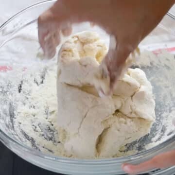 Closeup shot of kneading dough with hands in glass bowl. 